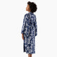 A woman shown from the back wearing a long-sleeve navy blue robe with a white palm tree pattern, standing against a plain white background.