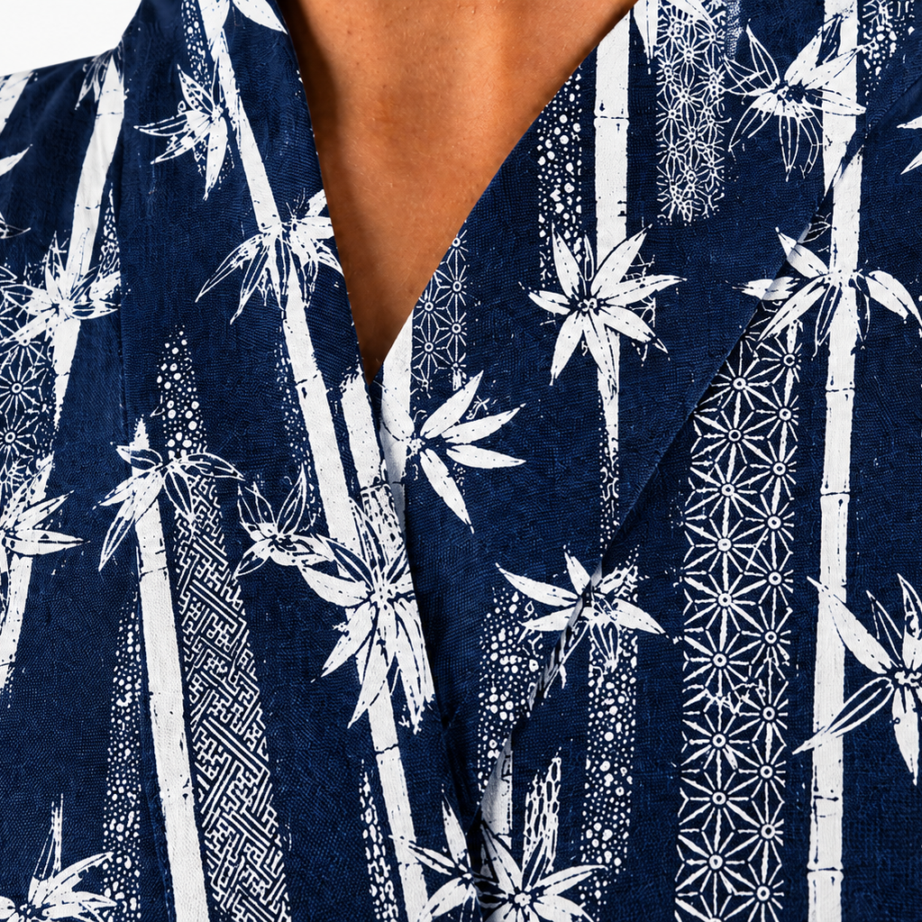Close-up of a navy blue kimono-style top with a white bamboo and floral pattern, worn by a model.