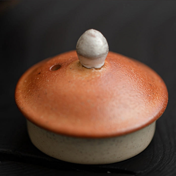 Ceramic pot with a textured brown lid on a black background