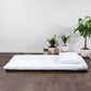 A traditional Japanese futon mattress in white, displayed on a flat surface, representing the tatami mat component of the bundle.