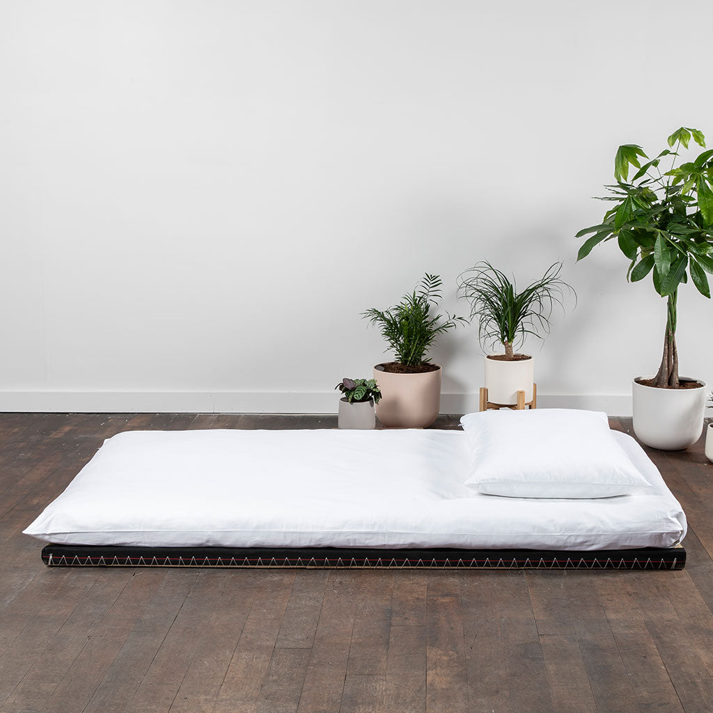 A traditional Japanese futon mattress in white, displayed on a flat surface, representing the tatami mat component of the bundle.