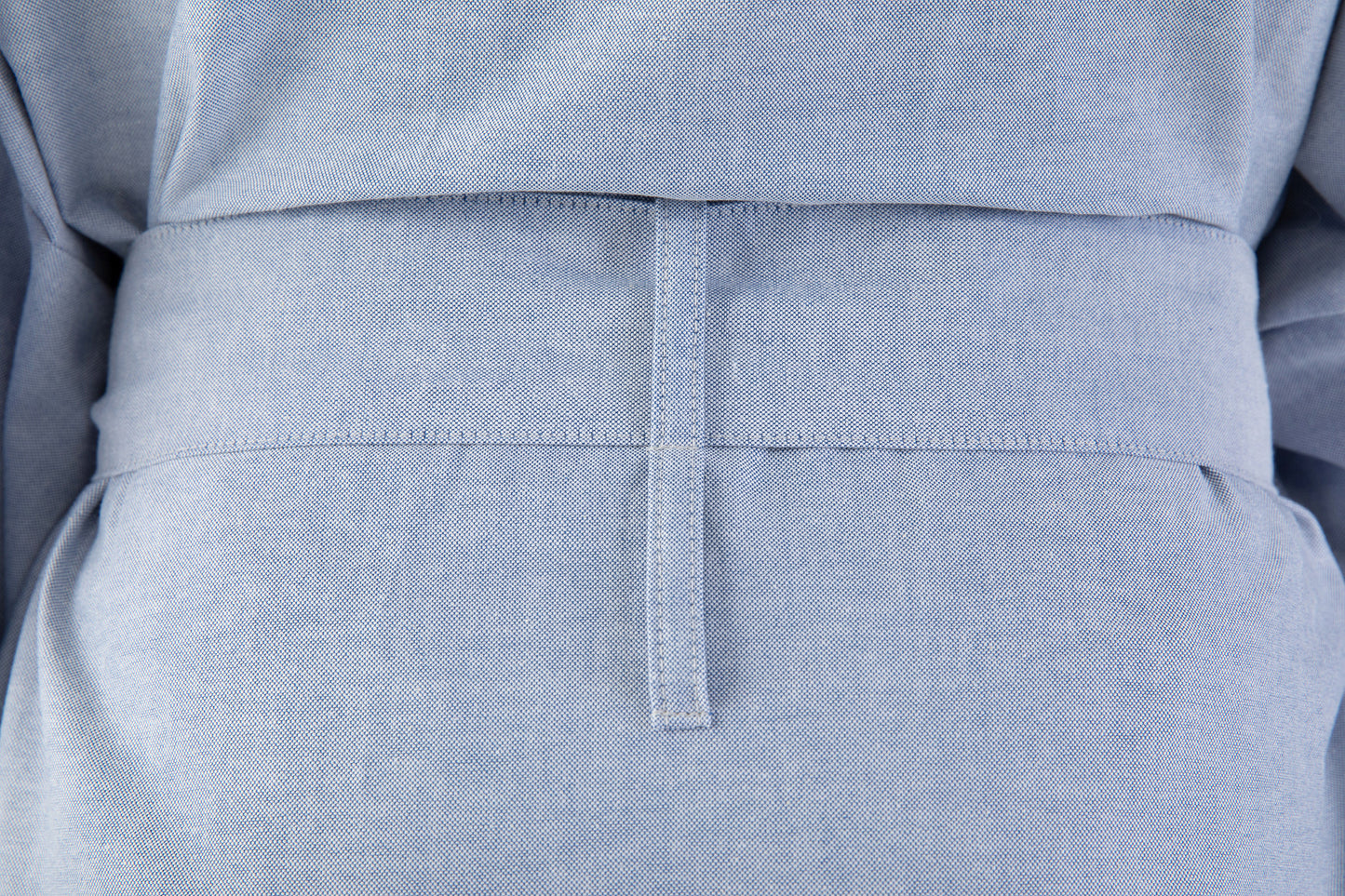 Close-up of a light blue garment with a belt and pocket detail.