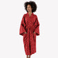 A woman wearing a red kimono-style robe with a white floral pattern, standing against a plain white studio background.