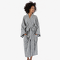A woman wearing a long-sleeved, tie-front robe with a black and white geometric pattern, standing against a plain white studio background.