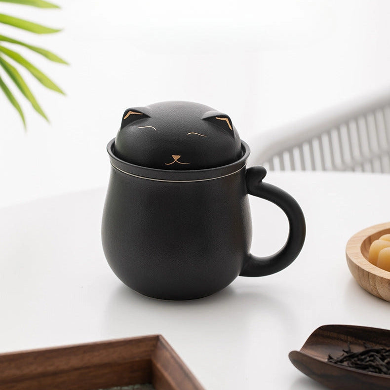 Black cat-shaped mug with a lid on a white surface with a plant in the background