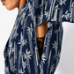 Close-up of a person wearing a navy blue kimono-style top with a white bamboo and leaf print, showing part of the chest, arm, and a dark brown lace insert.