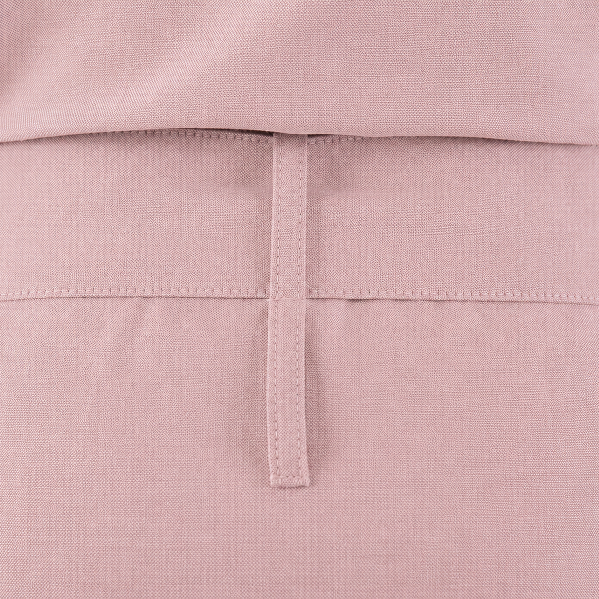 Close-up of a dusty pink garment showing the back waistband with a vertical stitched tab detail.